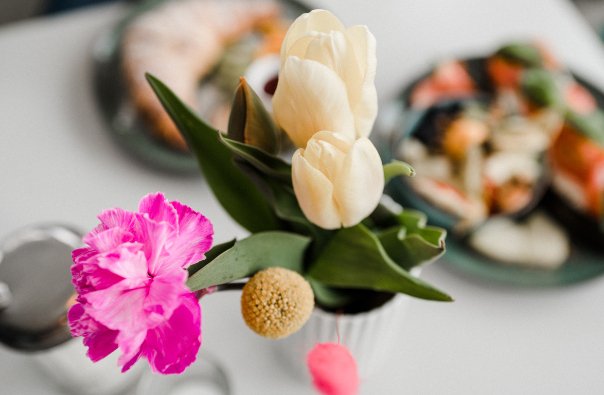Blumen und im Hintergrund etwas verschwommen ein leckeres Frühstück